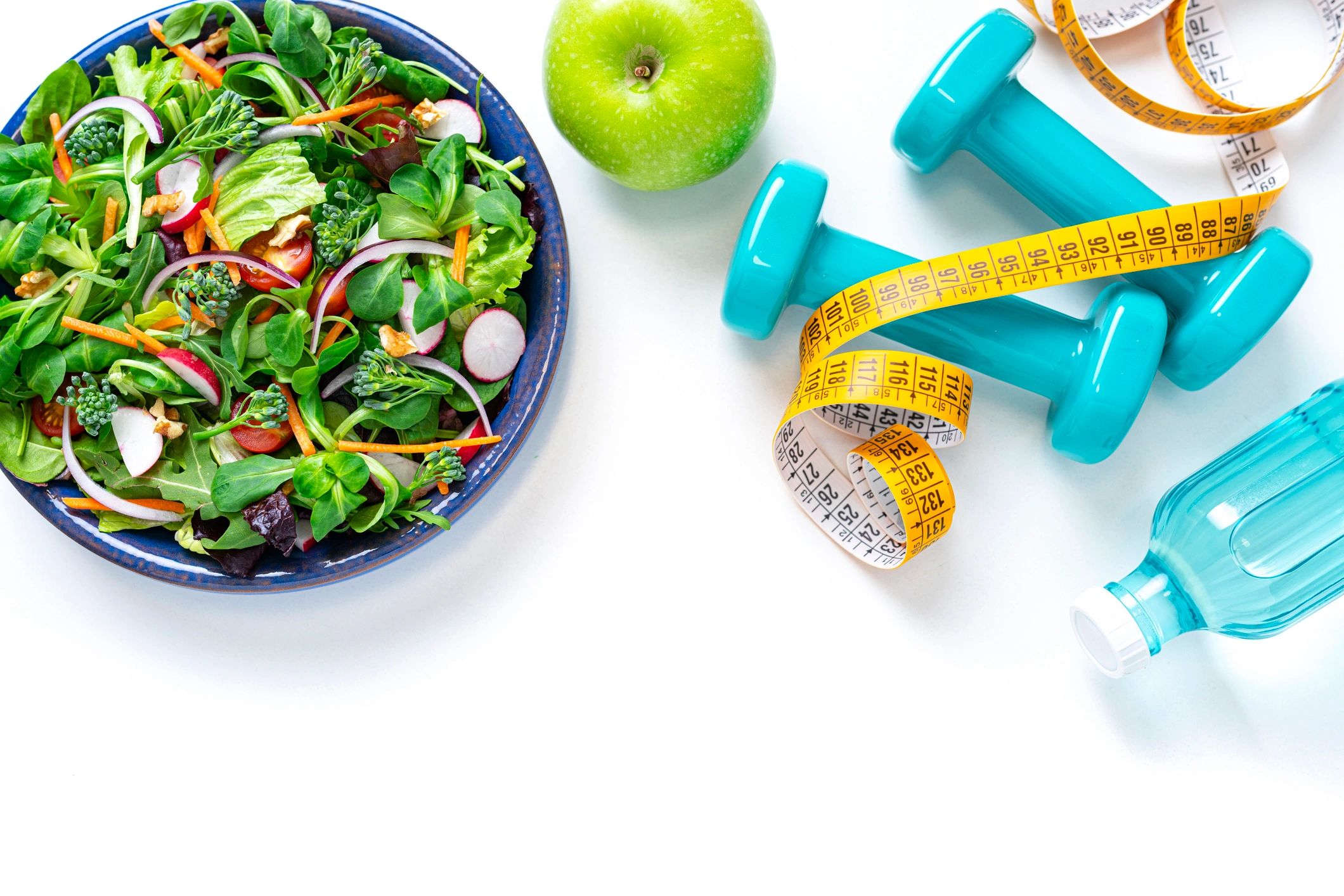 Water bottle and fitness equipment beside healthy food