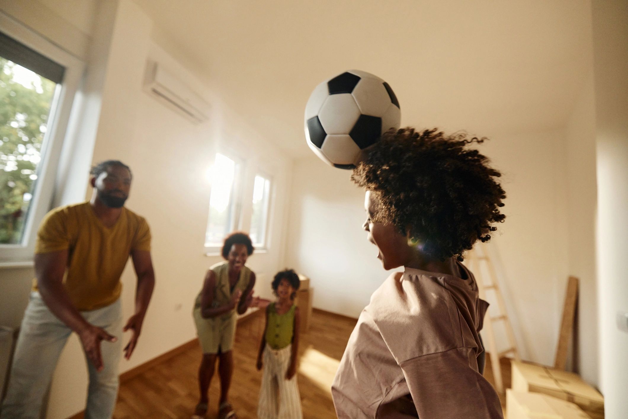 Child heading a football while family cheers