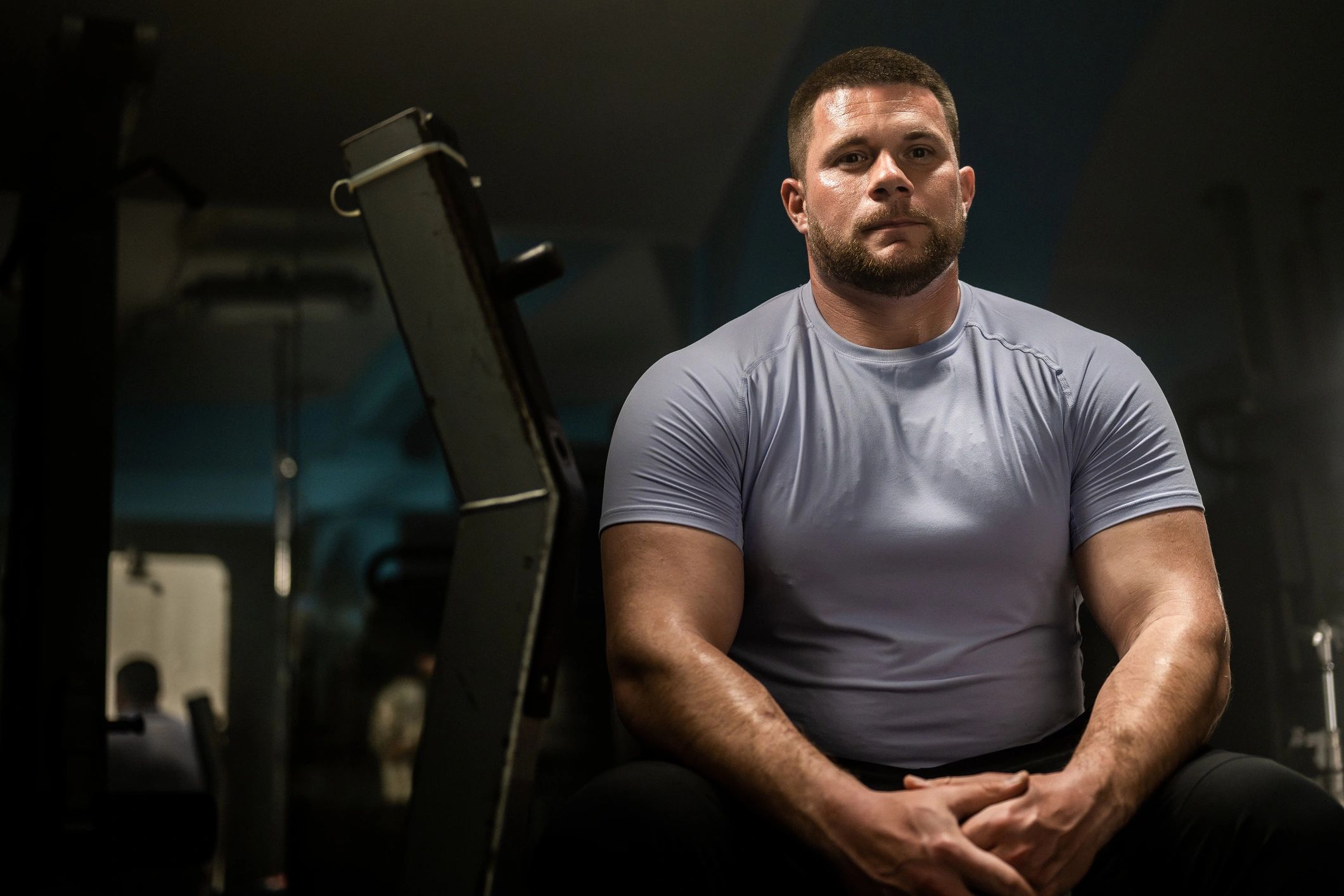 Football athlete resting between strength exercises in the gym