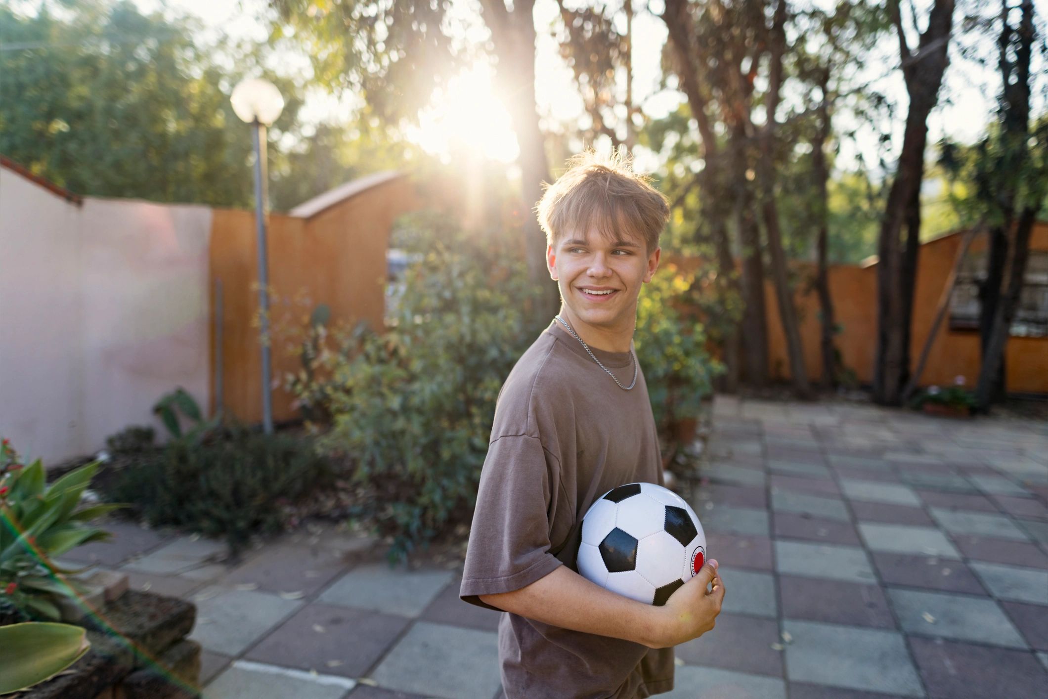 Young footballer walking with a ball in a sunny courtyard