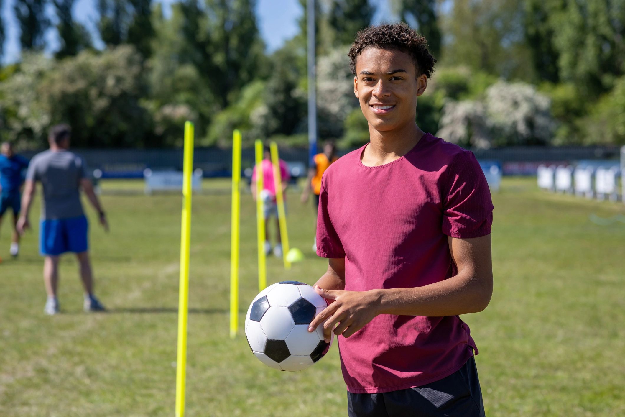 Young football player posing confidently with a ball on the pitch